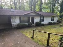 Charming single-story home with dark shutters, green shrubbery, and a driveway, set in a verdant, wooded neighborhood at 1184 Alemeda Dr, Marietta, GA 30066