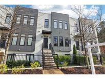 Modern townhome with white brick, gray panels, black framed windows, and black iron fences and stairs at 1098 Briar Cove Cir, Atlanta, GA 30329
