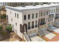 Elegant brick townhome featuring a two-car garage, arched entry and meticulously landscaped front yard at 255 Marjean Way, Alpharetta, GA 30009