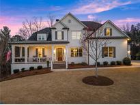 Inviting white brick home with a charming front porch and manicured lawn exudes classic elegance at 6455 Quiet Cove Rd, Cumming, GA 30041