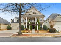 Two-story home featuring a charming front porch, manicured landscaping, and attached garage at 654 Crystal Cove Ct, Loganville, GA 30052
