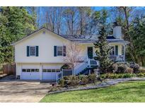 Charming yellow home featuring a two-car garage and a welcoming front porch with landscaped front yard at 2426 Westland Way, Acworth, GA 30102