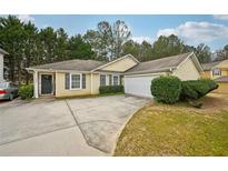 Charming single-story home with a well-maintained front yard and an attached two-car garage at 7595 Waverly Loop, Fairburn, GA 30213