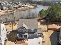 Beautiful two-story gray home with a three-car garage, nestled near a tranquil lake and lush green trees at 6145 Stargazer Way, Cumming, GA 30028
