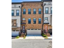 Three-story brick townhome featuring a two-car garage and covered front entrance at 1047 Brandsford Nw St, Atlanta, GA 30318