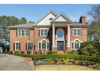 Stately brick home featuring a manicured lawn, mature landscaping, and classic architectural details at 5400 Saint Lyonn Pl, Marietta, GA 30068