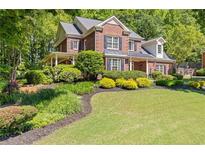 Charming two-story brick home with lush landscaping and a covered front porch at 2802 Nettle Ln, Buford, GA 30519