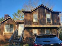 Two-story home with brown wooden exterior, stairs leading to the front door, and a black car parked in front at 1085 Mainstreet Valley Dr, Stone Mountain, GA 30088