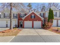 Charming townhome featuring a brick facade, two-car garage, and well-maintained landscaping at 2033 Fosco Dr, Duluth, GA 30097