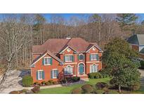Traditional red brick home with manicured lawn and blue shutters on a tree-lined lot at 775 River Cliff Ct, Suwanee, GA 30024