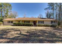 Ranch-style home featuring a manicured lawn, mature trees, and a welcoming facade at 150 Hickory Rd, Fayetteville, GA 30214