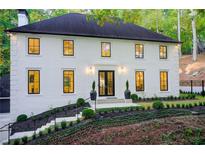 Stunning two-story home featuring a freshly painted white brick, a dark roof, and professionally landscaped front yard at 6090 River Chase Cir, Atlanta, GA 30328