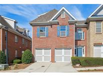 Charming brick townhouse with a two-car garage and beautiful blue shutters and matching front door at 10288 Quadrant Ct, Alpharetta, GA 30022