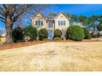 Charming two-story home with a well-manicured lawn, a blue front door, and mature trees in a suburban setting at 3287 Belmont Glen Se Dr, Marietta, GA 30067