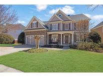 Charming two-story home with a manicured lawn, stone accents, and a welcoming covered porch area at 1728 Holcomb Lake Rd, Marietta, GA 30062