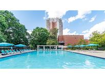 Enjoy the community pool with surrounding lounge chairs and a lush landscape, and a tall building in the background at 375 Ralph Mcgill Ne Blvd # 807, Atlanta, GA 30312