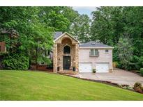 Beautiful brick home with a stone pillar entryway and a well-manicured lawn and mature tree coverage at 3290 Coachmans Ne Way, Roswell, GA 30075