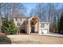 Stately brick two-story home featuring a stone entrance, attached two-car garage, and mature trees at 3290 Coachmans Way Ne Way, Roswell, GA 30075