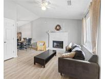 Bright living room features a fireplace, ceiling fan, and sleek gray sofa, blending comfort and style at 951 Orchard Mill Ln, Lawrenceville, GA 30043
