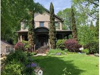 Charming home with a lush front yard, featuring a covered porch, mature landscaping, and a welcoming entrance at 1214 Oglethorpe Ne Ave, Brookhaven, GA 30319