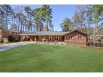 Charming brick home with a large, well-maintained front yard and mature trees providing shade at 3504 Palace Ct, Tucker, GA 30084