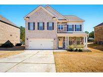 Charming two-story home with a brick and stone facade, a two-car garage, and a well-manicured front yard at 555 Birkdale Dr, Fairburn, GA 30213