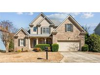Charming brick home featuring manicured landscaping, a two-car garage, and a welcoming front porch at 3262 Emerald Brook Ln, Decatur, GA 30033