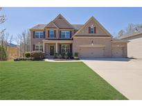 Beautiful two-story brick home with a well-manicured lawn and three-car garage at 194 Lakestone Parkway, Woodstock, GA 30188