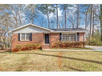 Charming red brick single-story home with black shutters and mature landscaping at 2718 Amelia Ave, Decatur, GA 30032