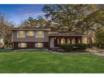 Charming split-level home with brick facade, landscaped front yard, and covered porch at 2670 Foxlair Trl, Atlanta, GA 30349