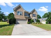 Charming two-story brick home with a well-manicured lawn, lush landscaping, and an attached two-car garage at 3302 Mcever Woods Nw Cir, Acworth, GA 30101