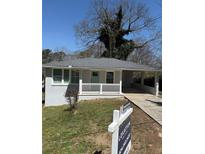 Charming single-story home featuring a welcoming front porch and a gray brick facade with covered parking at 2405 Cross Nw St, Atlanta, GA 30318