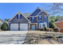 Charming two-story home featuring a two-car garage, landscaped yard, and a welcoming light blue front door at 5930 Crescent Landing Dr, Cumming, GA 30028