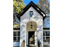 A beautiful home featuring a white facade, arched doorway, and a modern black door, complemented by stylish black hardware and lighting at 3629 Stewart Rd, Atlanta, GA 30340