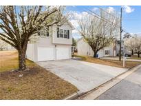 Two-story home featuring a two-car garage and a long driveway lined with lovely flowering trees at 4314 Ward Bluff Ct, Ellenwood, GA 30294