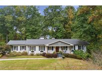 Charming one-story home featuring a manicured lawn, classic shutters, and a welcoming front porch swing at 6710 River Springs Ct, Atlanta, GA 30328