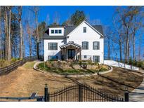 An inviting two-story white home featuring a well-manicured yard and a charming black wrought-iron gate at 1200 Primrose Park Rd, Sugar Hill, GA 30518