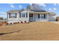 Charming home featuring a well-manicured lawn, solar panels, black shutters, and an attached garage at 6324 Amberly Rd, Rex, GA 30273