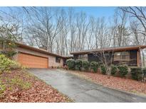 Charming single-story home with brick and dark siding, front yard landscaping and two-car garage at 357 Forest Lake Rd, Lawrenceville, GA 30046