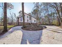 Contemporary home with a circular driveway and stone accents, surrounded by trees at 4013 Brenteresa Ct, Snellville, GA 30039