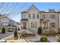 Charming exterior of a two-story townhome, featuring brick and hardiplank accents, professional landscaping, and covered entry at 1828 Falling Sky Ct, Atlanta, GA 30319
