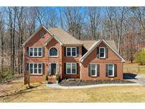 Charming two-story brick home with a well-manicured lawn and mature trees in a serene setting at 1880 Oak Wind Ln, Buford, GA 30519
