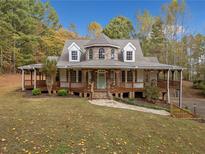 Charming two-story home featuring a covered porch, beautiful stone pathway, and surrounded by lush trees at 1655 Fate Conn Rd, Canton, GA 30114