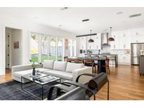 Open-concept living room featuring hardwood floors, modern sofa, and view into a bright, white kitchen at 56 Walthall Ne St, Atlanta, GA 30307