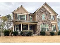 Charming two-story home featuring stone accents, neutral siding, and a welcoming front porch with rocking chairs at 8340 Nolandwood Ln, Villa Rica, GA 30180
