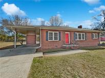 Charming brick home featuring a bright red front door and convenient covered parking area at 6120 E Fayetteville Dr, Riverdale, GA 30296