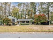 Charming one-story home with green siding, black shutters and mature trees at 2431 Weatherford Ct, Marietta, GA 30068