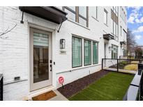 Modern townhome featuring a white brick facade, artificial grass, and dark trim at 304 Gibson Se St, Atlanta, GA 30316