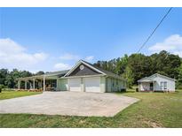 Charming home exterior with a large, paved driveway, two-car garage, covered porch, and a well-maintained lawn at 410 Bowen Ne Rd, White, GA 30184