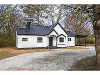 Charming renovated home with black trim, black roof, gravel driveway, and a covered carport at 65 Sage St, Temple, GA 30179